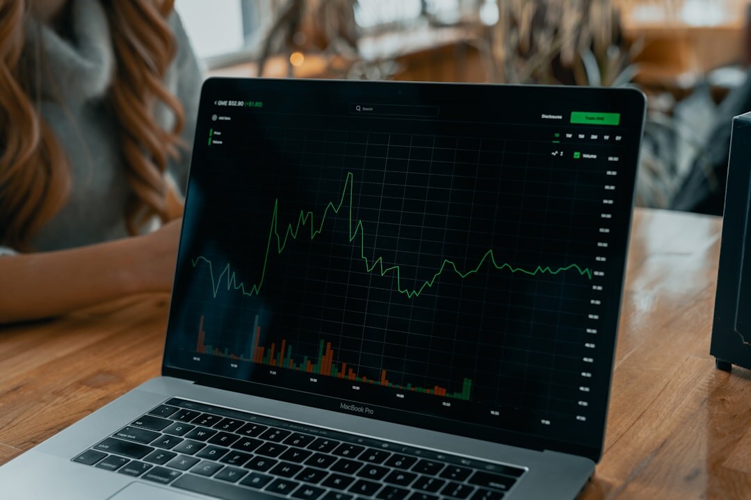 Desk with charts, graphs and a laptop showing market data